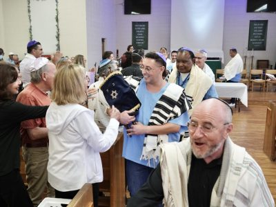 Tony Tafoya, center with the Torah scroll, leads a procession during the bar mitzvah service at San Quentin Rehabilitation Center, July 16, 2026, in San Quentin, Calif. (Marcus Casillas/San Quentin News)